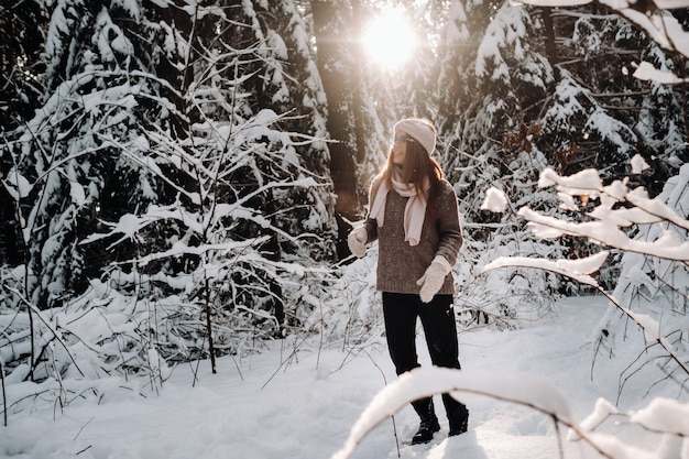 Uma garota com um suéter e óculos no inverno em uma floresta coberta de neve