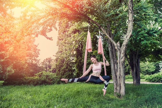 Uma garota com um tipo de figura magra decidiu praticar exercícios de ioga ao ar livre com bom tempo Conceito de mosca de ioga ao ar livre na árvore