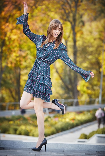 Uma garota com um vestido azul no fundo de um parque de outono