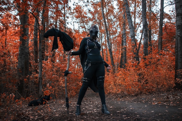 Uma garota com uma fantasia de bdsm e uma máscara preta em uma ideia vermelha forest.an para o halloween.