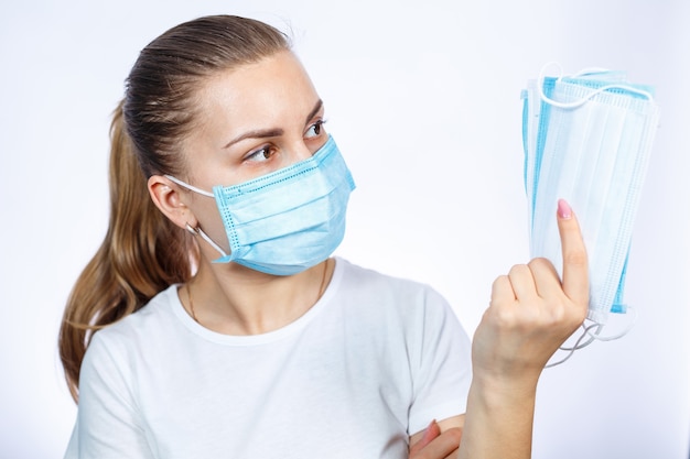 Foto uma garota com uma máscara médica protetora segura nas mãos meios para proteger o trato respiratório contra o vírus.