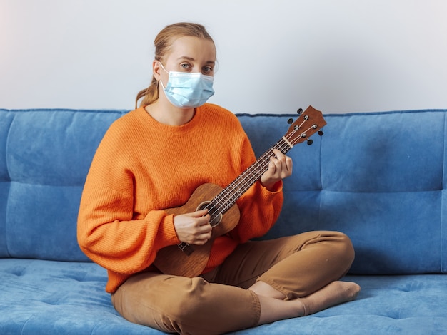 Uma garota com uma máscara médica tocando ukulele
