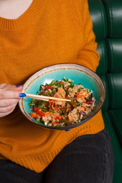 Uma garota come arroz de alho com camarão em um restaurante