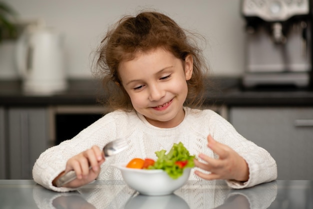 Uma garota come uma salada de legumes frescos O conceito de alimentação saudável Comida saudável Infância