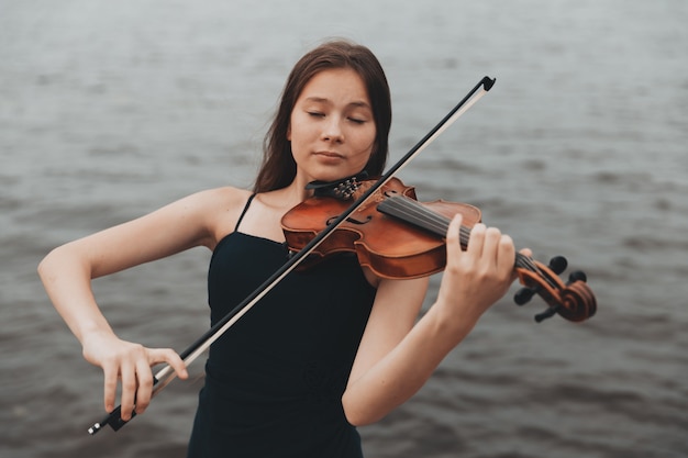 Uma garota de aparência asiática toca violino na natureza. foto de alta qualidade