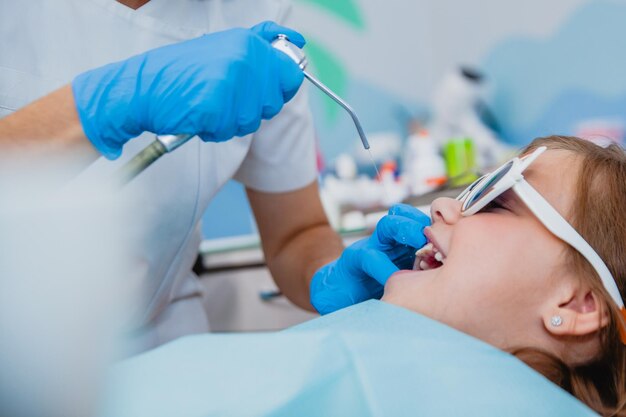 Foto uma garota de aparência européia em óculos de sorriso engraçados recebe tratamento dentário com sorriso