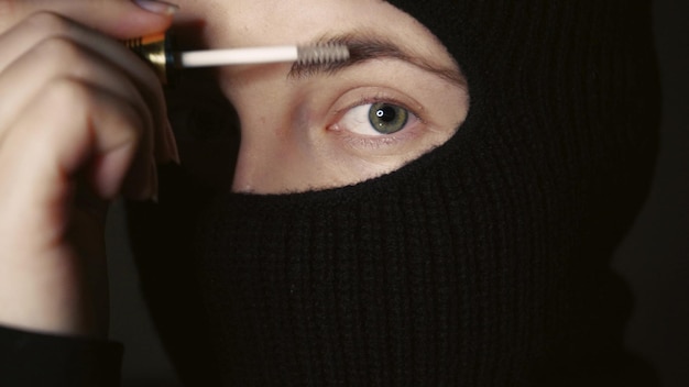 Uma garota de balaclava faz maquiagem Uma mulher de hijab pinta os olhos Uma linda garota de burca aplica maquiagem no rosto Conceito de beleza e moda Closeup foto macro