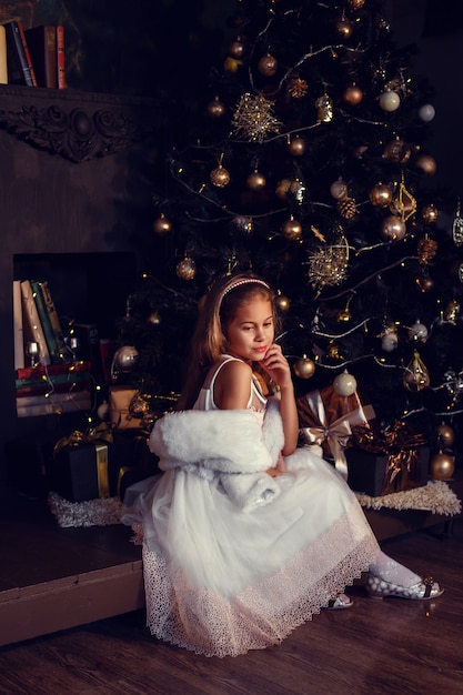 Uma garota de cabelo castanho ao lado de uma árvore de natal