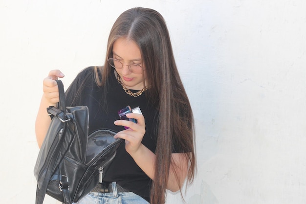 Uma garota de cabelo escuro tira um frasco de perfume de sua mochila