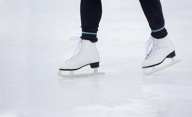 Uma garota de calça preta patina no gelo do estádio durante o dia