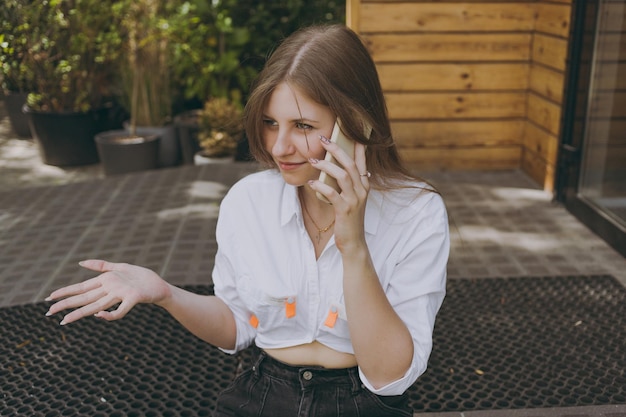 Uma garota de camisa branca na cidade falando ao telefone