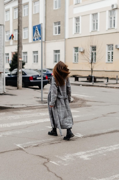 uma garota de casaco atravessa a rua