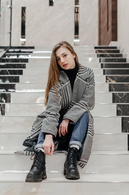 uma garota de casaco senta-se na escada