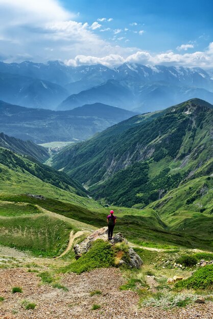 Uma garota de chapéu fica em uma pedra no fundo das montanhas Svaneti Cáucaso no verão