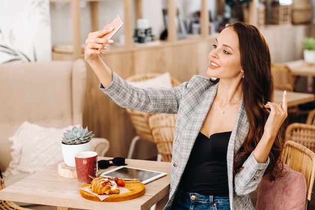 Uma garota de negócios está sentada em um café e tirando uma selfie