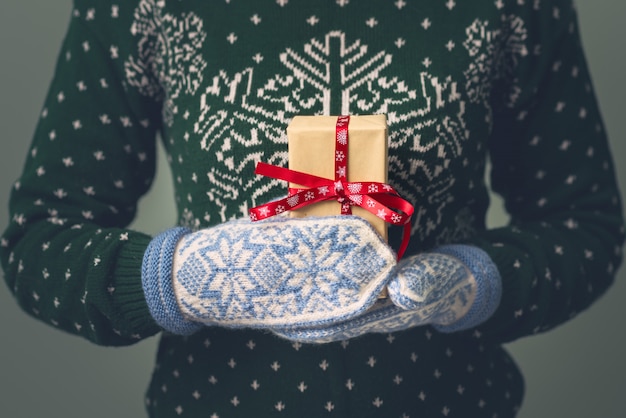 Uma garota de suéter de ano novo tem um presente. presentes para homens. feliz natal. presente para uma menina. camisola com enfeite de natal. vestido de malha.