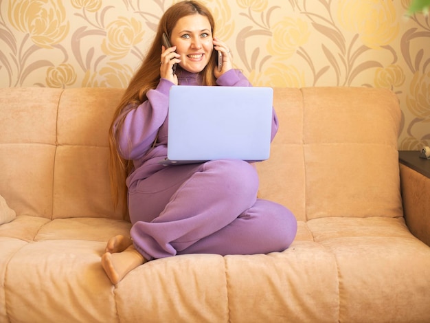 Foto uma garota de terno roxo com um laptop no sofá se comunicando nas redes sociais