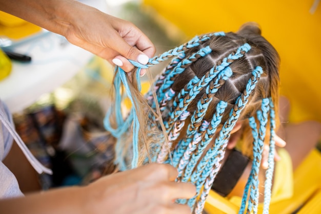 Uma garota de terno tece tranças africanas no cabelo em um dia ensolarado