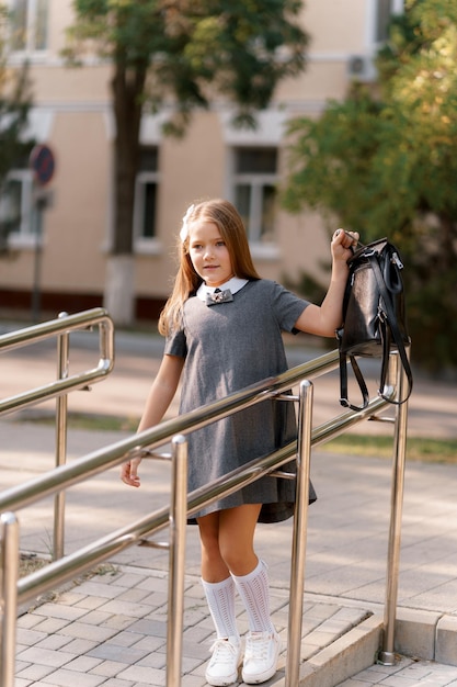 uma garota de uniforme escolar em um vestido cinza caminha no parque