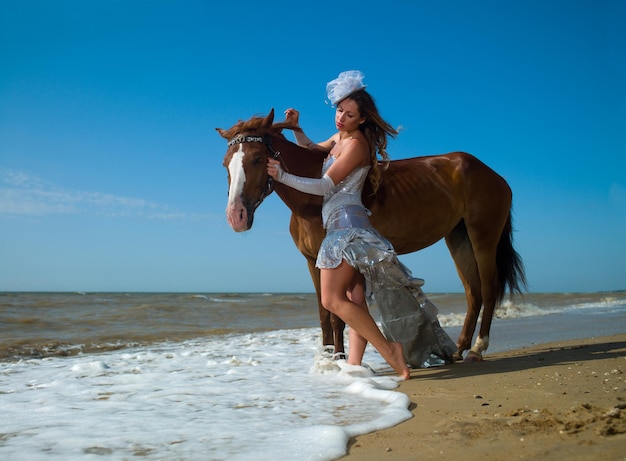 Uma garota de vestido branco ao lado de um cavalo na praia