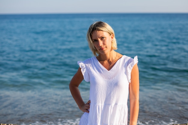 Uma garota de vestido branco caminhando à beira-mar