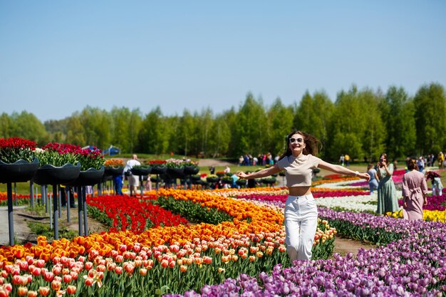 Uma garota de vestido branco corre entre as tulipas Campo com tulipas amarelas e vermelhas