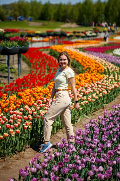 Uma garota de vestido branco corre entre as tulipas Campo com tulipas amarelas e vermelhas