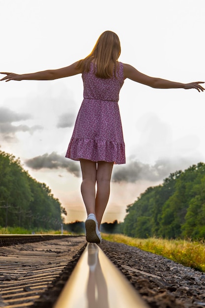 Foto uma garota de vestido caminha pelos trilhos