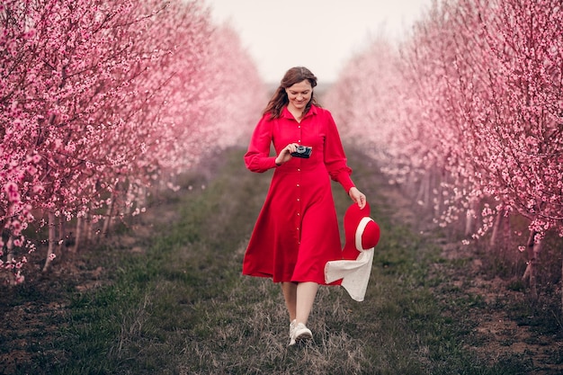 Uma garota de vestido vermelho anda no jardim com cachorro Lady in red