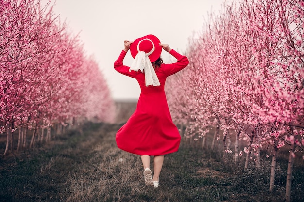 Uma garota de vestido vermelho anda no jardim com cachorro Lady in red