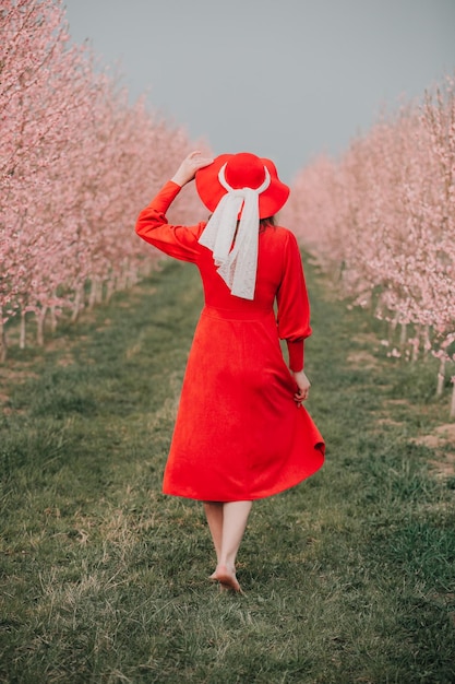 Uma garota de vestido vermelho caminha no jardim primavera