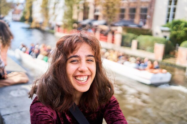 Foto uma garota de vestido vermelho de cordel com as costas abertas caminha pelas ruas de bruges num dia de outono.