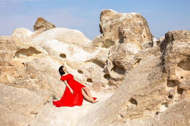 Uma garota de vestido vermelho descansa perto das cavernas na Capadócia Turquia