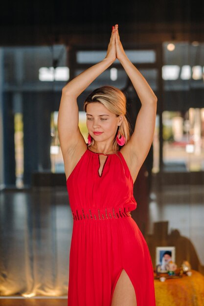 Uma garota de vestido vermelho se move em uma dança meditando dança dinâmica dentro de casa