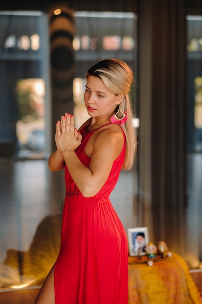 Uma garota de vestido vermelho se move em uma dança meditando dentro de casa Dança dinâmica