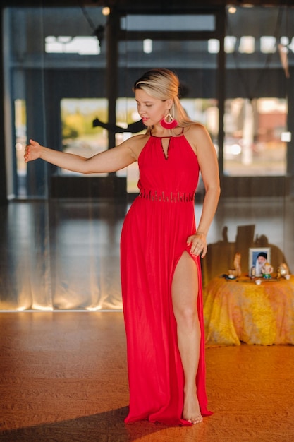 Uma garota de vestido vermelho se move em uma dança meditando dentro de casa Dança dinâmica