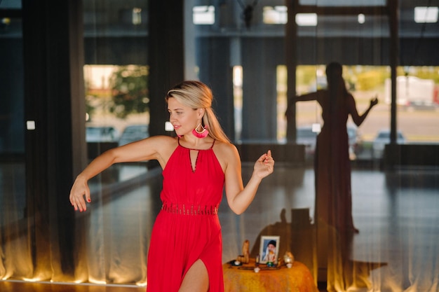 Uma garota de vestido vermelho se move em uma dança meditando dentro de casa Dança dinâmica