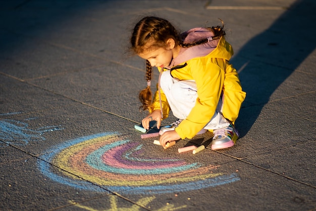Uma garota desenha um arco-íris nos raios do pôr do sol