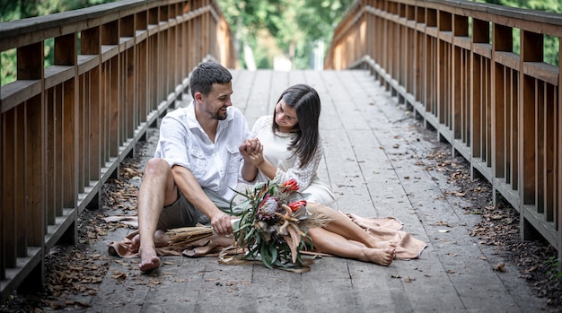 Uma garota e um jovem sentam-se na ponte e apreciam a comunicação, um encontro na natureza, uma história de amor.