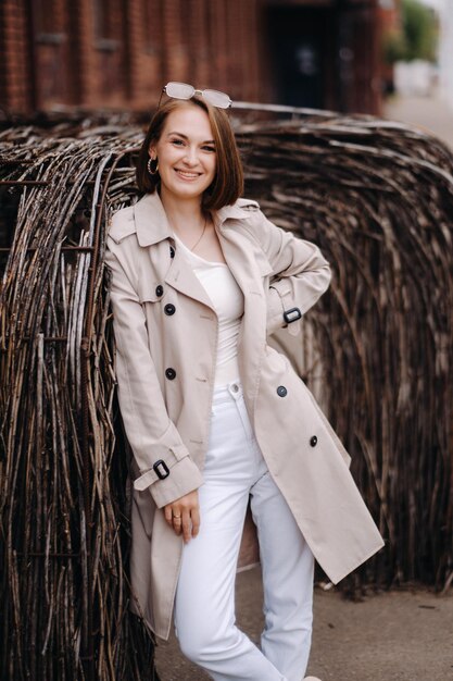 Uma garota elegante e feliz com um casaco cinza anda pela cidade