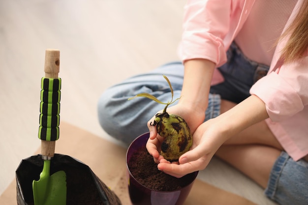 Foto uma garota em casa tem uma semente de manga em um vaso de flores instruções passo a passo etapa dois