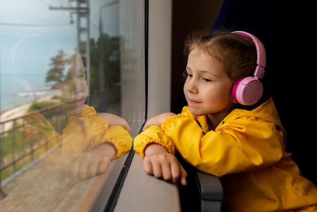 Uma garota em fones de ouvido em um trem olha pela janela Journey