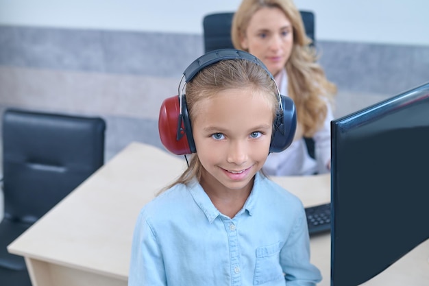 Uma garota em fones de ouvido fazendo um teste de audição na clínica