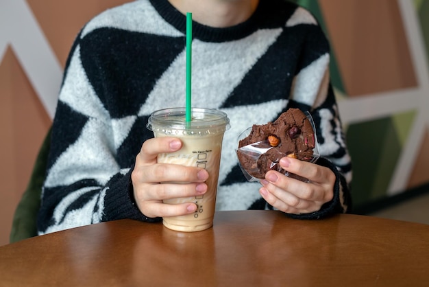 Uma garota em um café bebe café e come biscoitos de chocolate