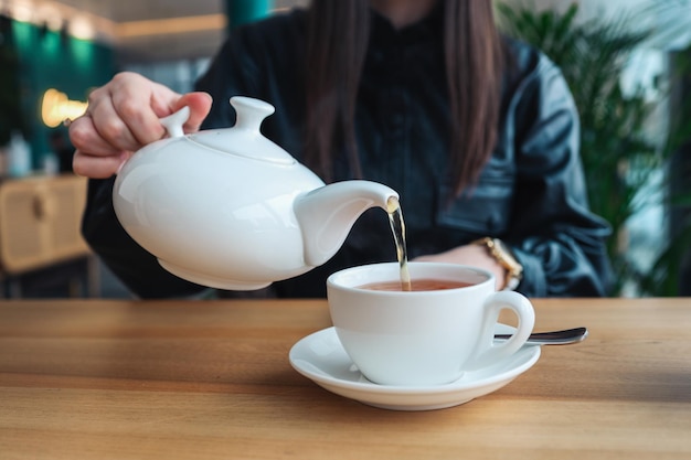 Uma garota em um café derrama chá em xícaras Linda foto aconchegante