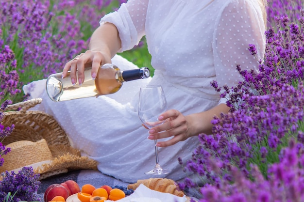 Uma garota em um campo de lavanda derrama vinho em um copo Relaxamento