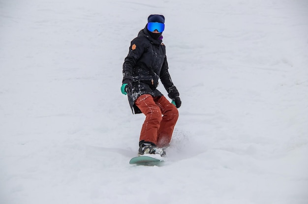 Foto uma garota em um snowboard desce a encosta da montanha