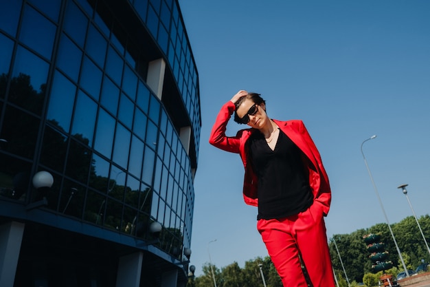 Uma garota em um terno vermelho está no fundo de um edifício moderno na cidade