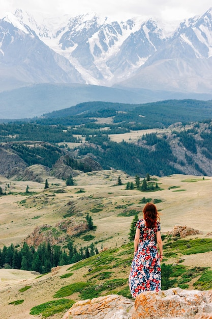 Foto uma garota em um vestido colorido contra o fundo majestoso de um vale de montanha com um desfiladeiro e um cume