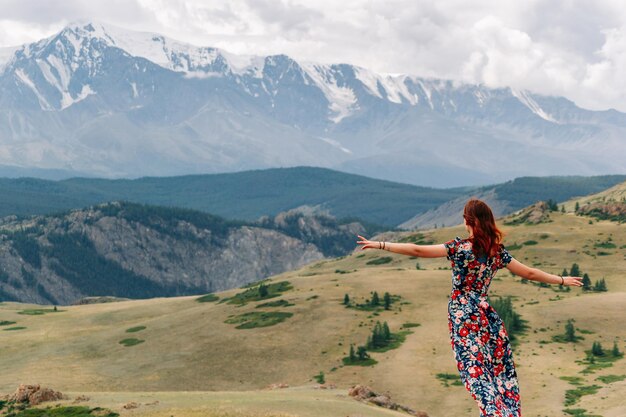 Uma garota em um vestido colorido contra o fundo majestoso de um vale de montanha com um desfiladeiro e um cume